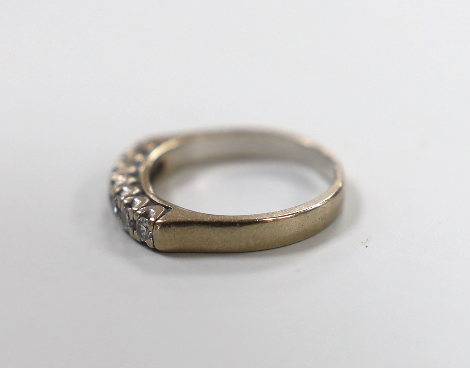 A modern white metal and seven stone diamond set half eternity ring, size L/M, gross weight 4.2 grams.